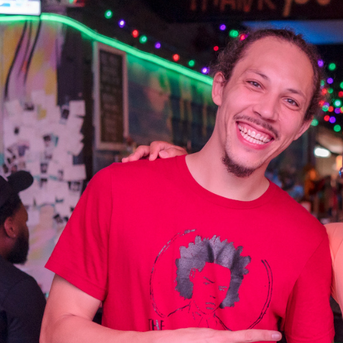 A person smiling with his hand on his shoulder
